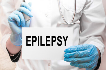The doctor's blue - gloved hands show the word EPILEPSY - . a gloved hand on a white background....