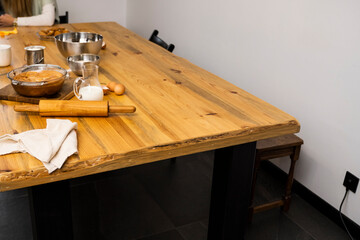 Tasty apple pie on a oaken wood table with a ingredients. Cooking a delicious apple pie on a kitchen in a loft style. Milk, eggs, sugar and a baked pie on a table. Home kitchen.
