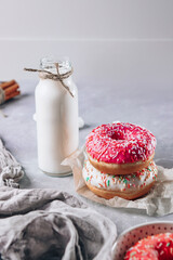  Bright pink donuts and a bottle of milk on the table, vertical photo