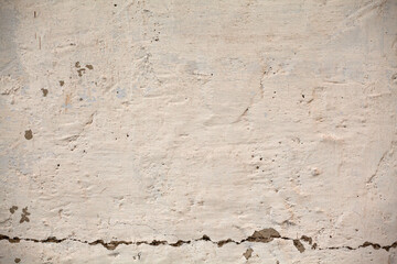 Old plastered wall with crumbling plaster and a crack at the bottom. Background, material for 3D, texture.