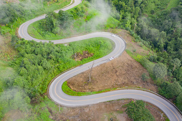 Aerial view of cars driving on curved, zigzag curve road or street on mountain hill with green...
