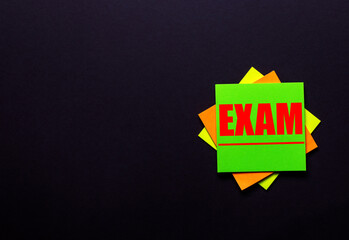 The word EXAM on a bright sticker on a dark background