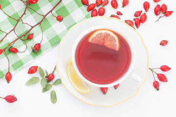 Cup of rose hip herbal tea with rose-hip fruits and pot on white background. Dog rose autumn or winter healthy tea. Strengthening the immune system.