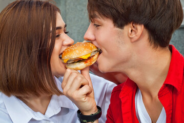Man and woman having lunch outdoors together. Couple eating burger and sandwich. The concept of...