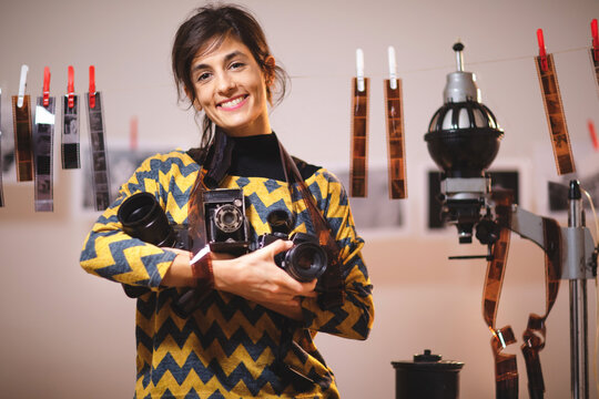 Portrait of beautiful female holding photo cameras in in photo studio