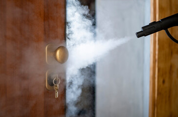 disinfection and sanitization with steam at home, steam flow is directed to the door handle and keys in the lock