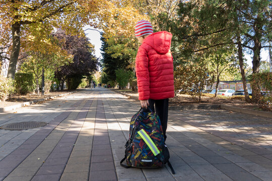 Schoolboy Is Dragging Very Heavy Backpack With School Stuff In It On His Way To School. Problem Of Too Many School Books Students Have To Carry On.