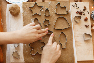 Person making Christmas gingerbread cookies, holiday advent. Hands cutting gingerbread dough