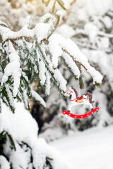 Toy horse on a snow-covered fir branch. Christmas tree in the snow and Christmas decorations. Christmas card.