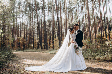 Fototapeta na wymiar Walk of the bride and groom in the summer forest. Beautiful outdoor photo session.