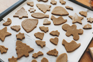 Raw gingerbread cookies in festive christmas shapes on oven tray. Cooking gingerbread cookies