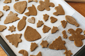 Cooking gingerbread cookies. Raw gingerbread cookies in festive christmas shapes on oven tray