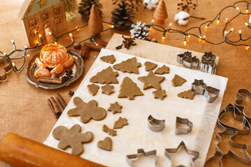 Raw gingerbread dough, wooden rolling pin, metal cutters, spices, festive decorations and lights