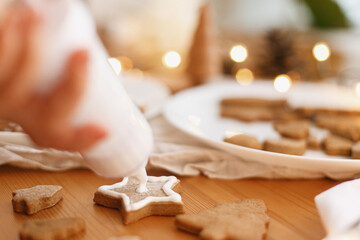 Hands decorating baked christmas star cookie with sugar frosting. Family christmas time