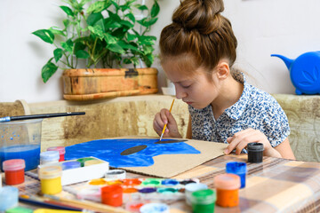 a girl drawing blue gouache cardboard, artistic creation at home, makes creative artwork