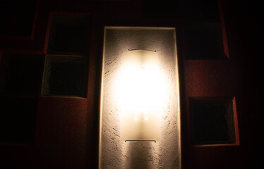 A lamp shines on a textured wall in the dark