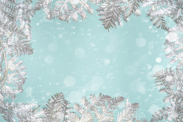 Fototapeta na wymiar Winter and Christmas Festive Snowy Background with Silver Xmas Decor Branches, over light blue background. Christmas and New Year greeting card concept, copy space