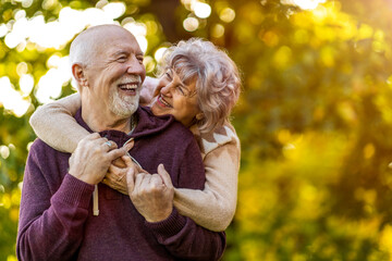 Happy senior couple spending time together in beautiful city park in autumn