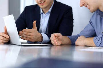 Fototapeta premium Business people using laptop computer while working together at the desk in modern office. Unknown businessman or male entrepreneur with colleague at workplace. Teamwork and partnership concept