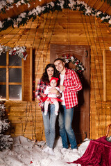 Mom and dad pose with their charming little daughter in decorated christmas studio. New Year photo session.