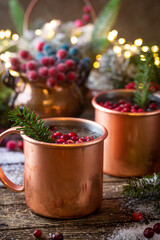Mulled wine with cranberry in copper mug with christmas decorations on wooden table