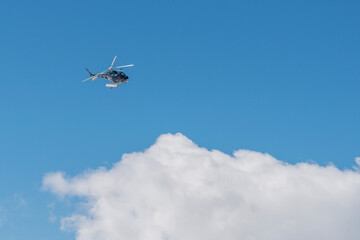 Helicopter on the sky in French French alps in winter, snowy mountains in France