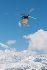 Fototapeta na wymiar Helicopter on the sky in French French alps in winter, snowy mountains in France