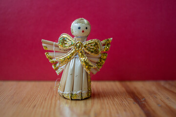 Straw Christmas ornament. Christmas angel on red background. Eco concept.