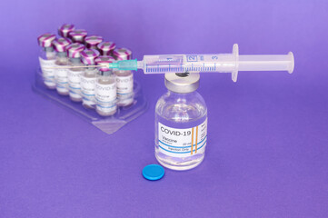 Coronavirus COVID-19 vaccine in vial and syringe, on purple background prepared for health, new...