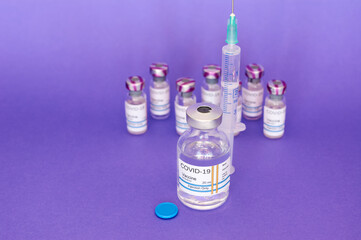 Coronavirus COVID-19 vaccine in vial and syringe, on purple background prepared for health, new...