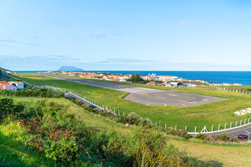 Fototapeta na wymiar Azores, island of Graciosa, view at the airport of Santa Cruz da Graciosa. th runway is near houses and church.