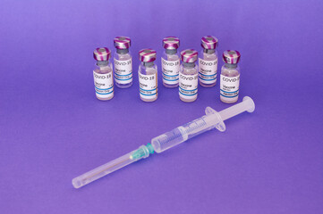 Coronavirus COVID-19 vaccine in vial and syringe, on purple background prepared for health, new...