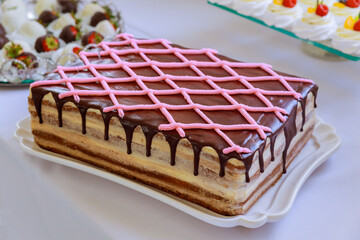 Rectangular chocolate cream cake decorated with pink buttercream.