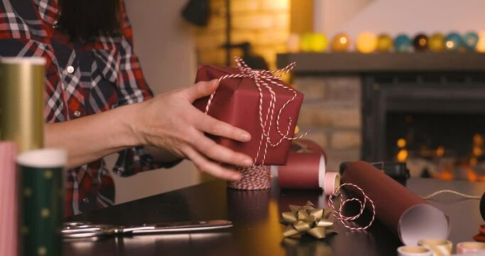 Gift workshop in a warm cozy room. Christmas decorations by fireplace. Women prepering Christmas gifts.