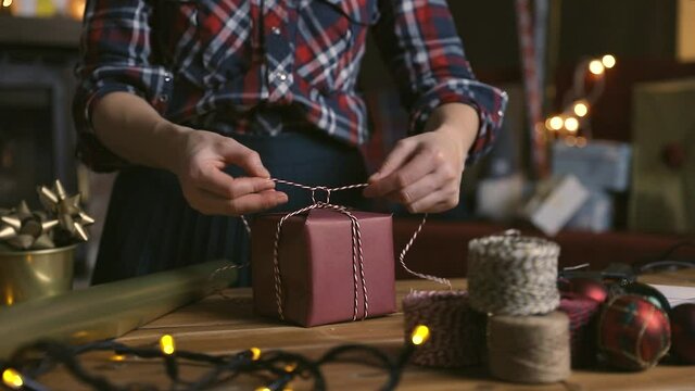 Gift workshop in a warm cozy room. Christmas decorations by fireplace. Women prepering Christmas gifts.