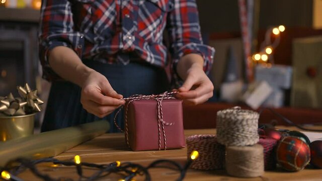 Gift workshop in a warm cozy room. Christmas decorations by fireplace. Women prepering Christmas gifts.