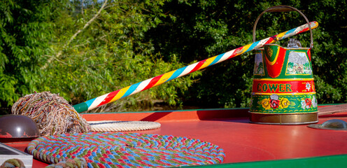 Beautifully hand painted traditional coal scuttle and mop on the roof of a narrow boat
