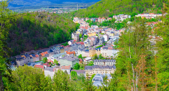Karlovy Vary city aerial panoramic view with colorful multicolored buildings and spa hotels in historical centre. Panorama of Karlsbad town and Slavkov Forest hills with trees on slope, Czech Republic © Aliaksandr