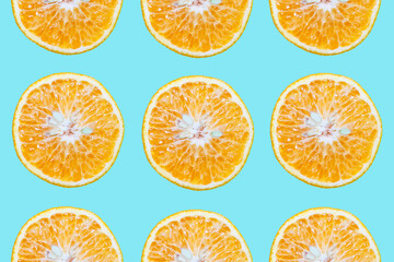 Colorful pattern of cutted orange fruits, isolated on background of cyan or aqua menthe color.