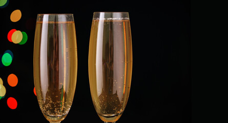 Two glasses with champagne vigraists and a bottle of champagne, lights, sideways, serpentine. New Year's content 2021.