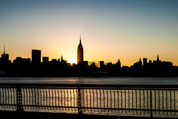 Buildings in silhouette along the New York City skyline in the early morning on the Hudson River, view from New Jersey.