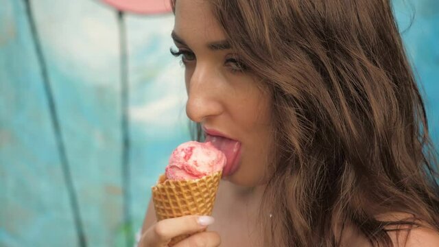 The girl in the park eats ice cream in a waffle cup. Brunette licking ice cream. Close up. Slow motion 180 frames per second.