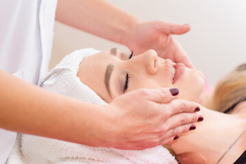 Fototapeta na wymiar beautician doing facial massage to woman in clinic