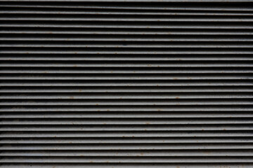 Gray metal louver grille. There are dirt and rust spots on the metal strips. Background. Texture.