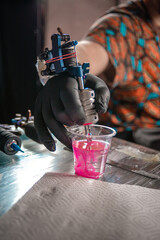 Hand of tattooer and a tattoo machine.