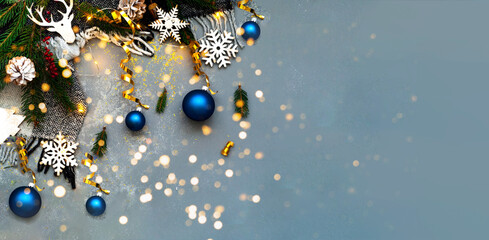 Festive grey background with sparkles. Christmas wooden figurines on fir branches. Creative copy space.