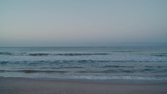 Calm and peaceful mediterranean sea waves wash over shore of sandy beach at sunset soft light. Mindfulness and relaxation concept. Space for copy text. Surf rolling over sand beach shoreline