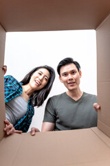 Asian attractive young couple opening a carton box and looking inside, they are excited and glad, to people and relocation concept