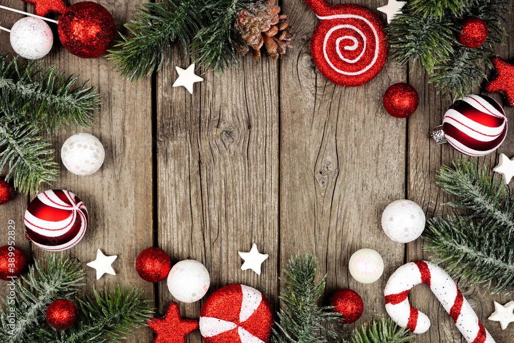 Poster christmas frame of red and white decorations with tree branches. overhead view on a dark wood backgr