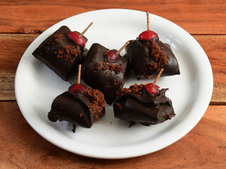 chocolate brownie flavored betel leaf on ice stuffed with cherry known as chocolate brownie paan. A widely loved mouth-freshener cum dessert recipe with selective focus on white plate